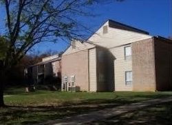 Apartment building with beige siding, windows, and a grassy yard under a blue sky.