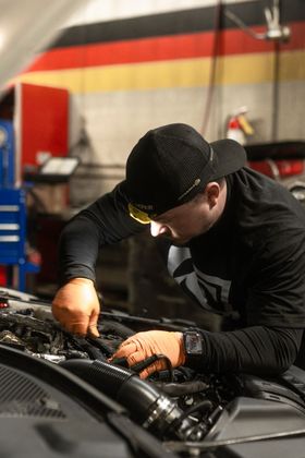 S&S Bavarian Auto Mechanic inspecting under car hood