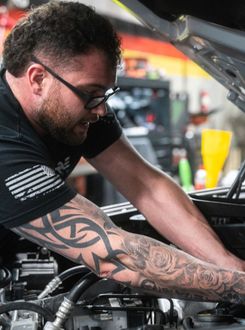 S&S Bavarian Auto Mechanic inspecting under car hood