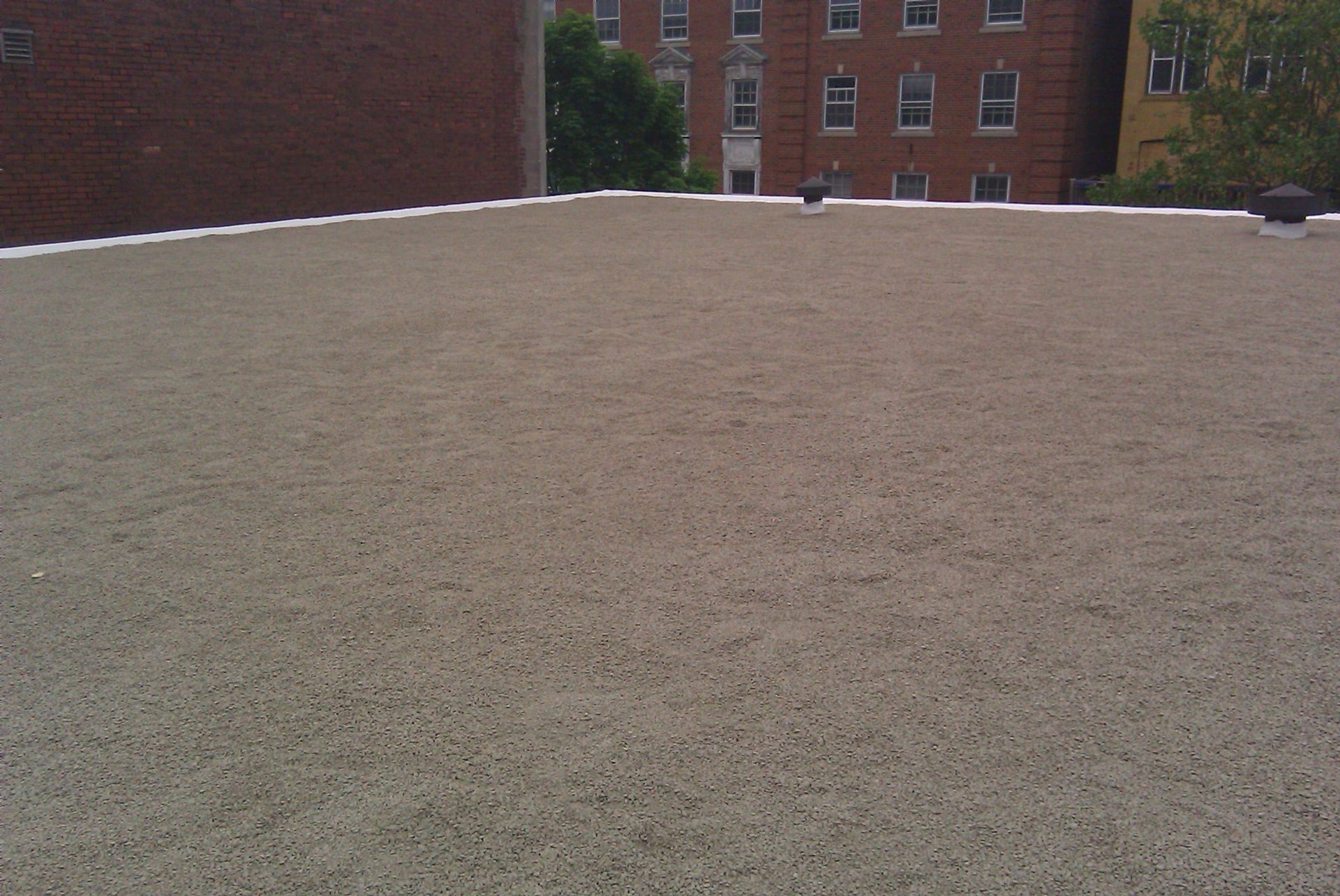 A roof with a brick building in the background