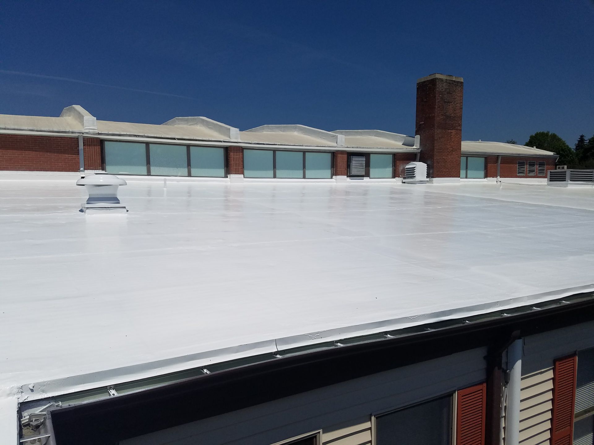 A white roof with a chimney on top of a building.