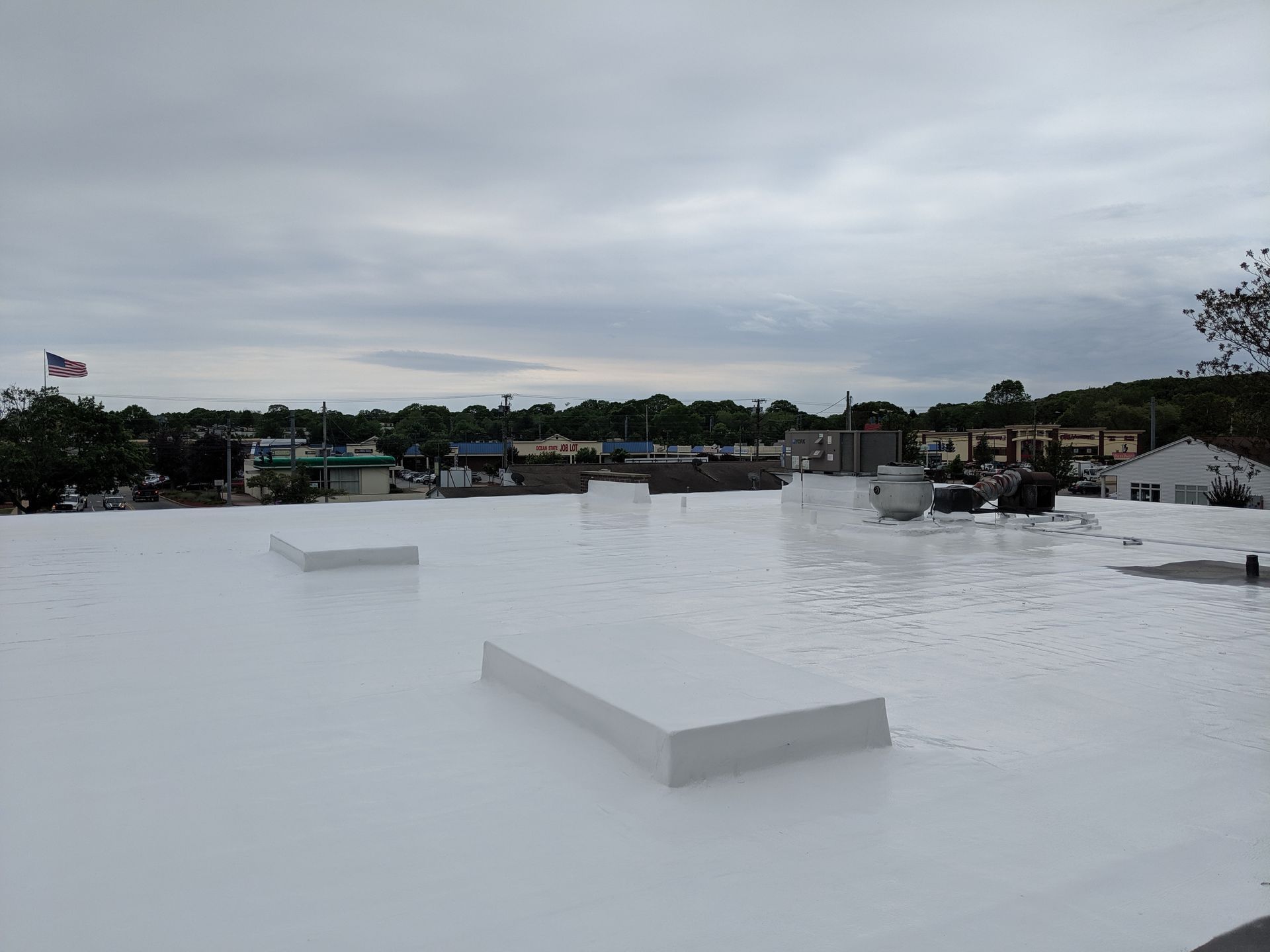 A white roof with a view of a city on a cloudy day.
