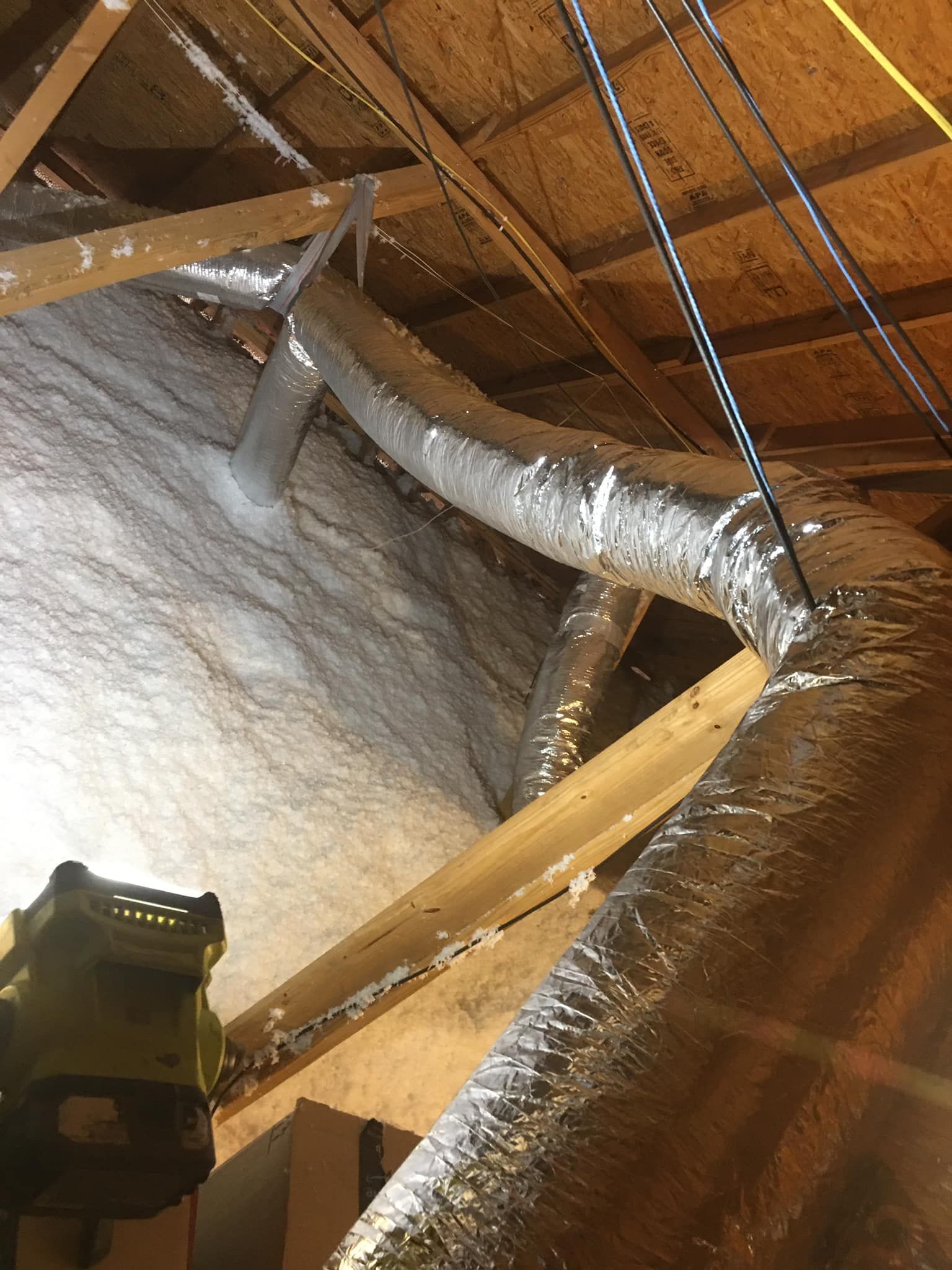 A vacuum cleaner is hanging from the ceiling of an attic.