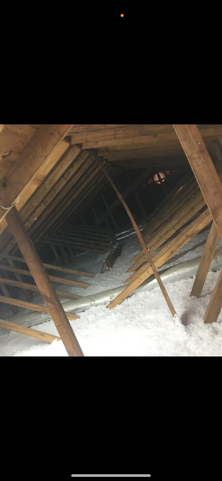 A picture of the inside of an attic with wooden beams and insulation.