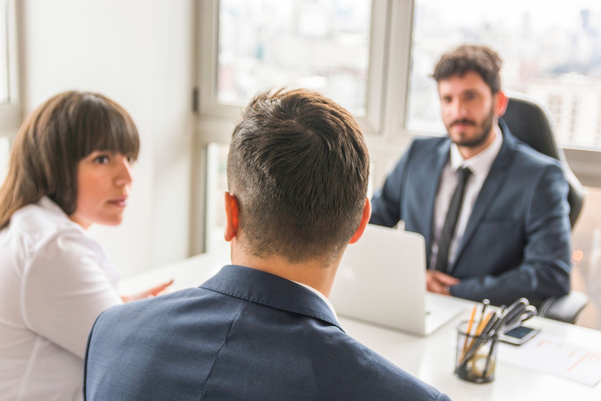 A man is sitting at a table talking to a woman and a man in a suit and tie.