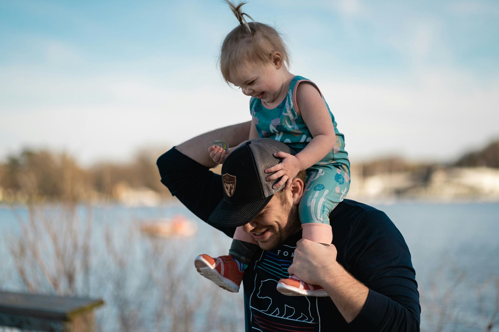 A man is carrying a little girl on his shoulders.