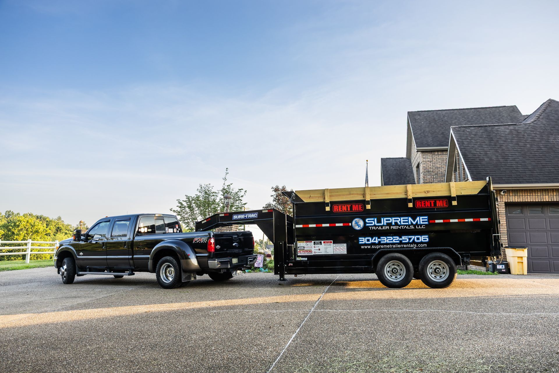 A black pickup truck towing a black dump trailer with