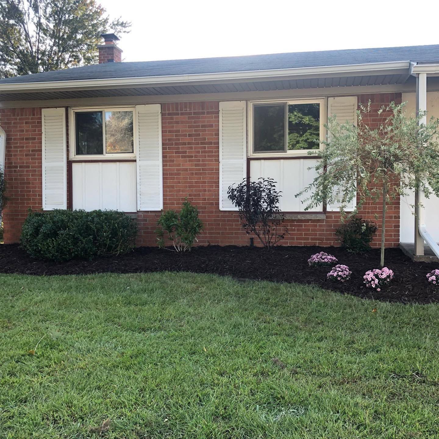 Single-story brick house with white shutters, front lawn, and landscaped shrubs.