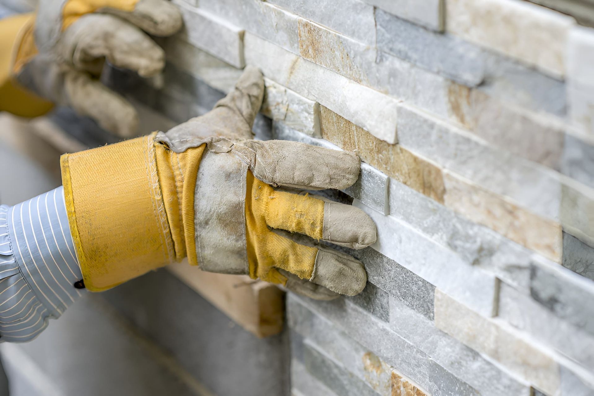 A Person Wearing Gloves Is Installing Granite Stone — Stone Theory In Queanbeyan West, NSW