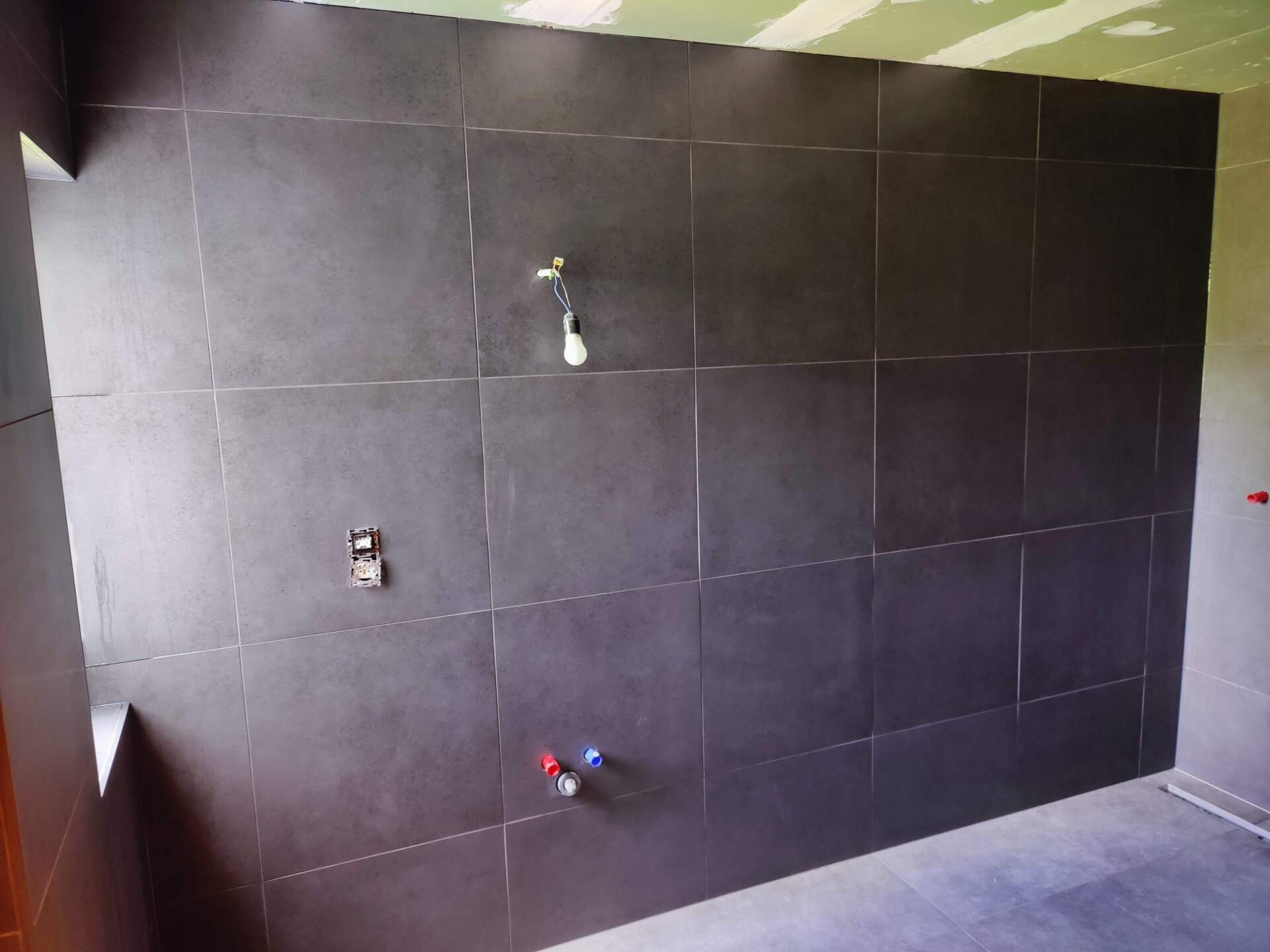 A bathroom with black tiles and a faucet on the wall