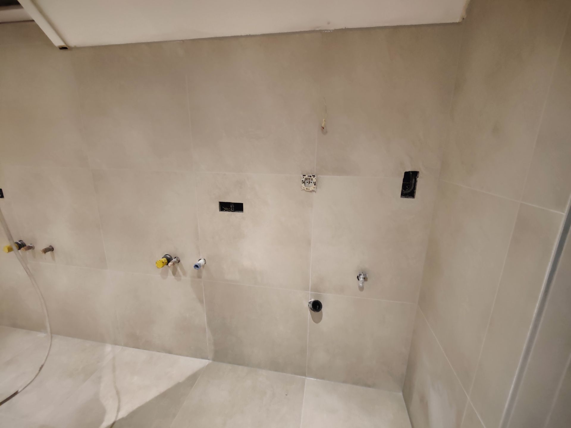 A bathroom with white tiles and black faucets.
