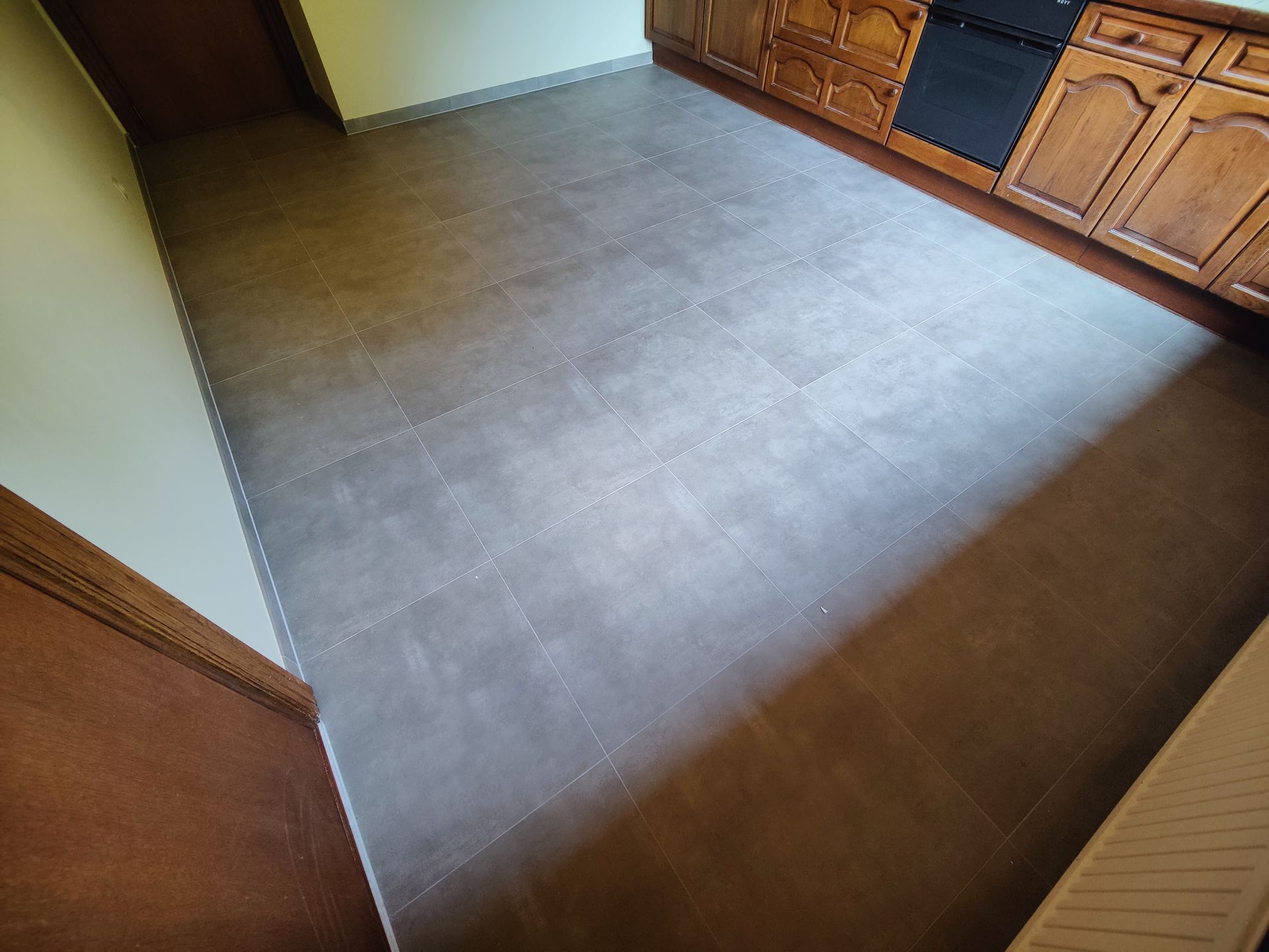 A kitchen with a tiled floor and wooden cabinets