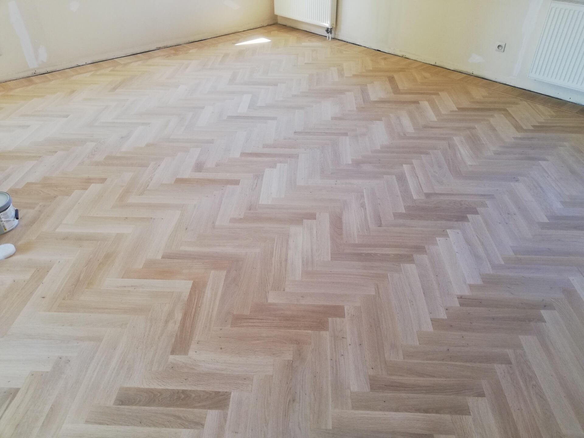A wooden floor with a herringbone pattern in a room.