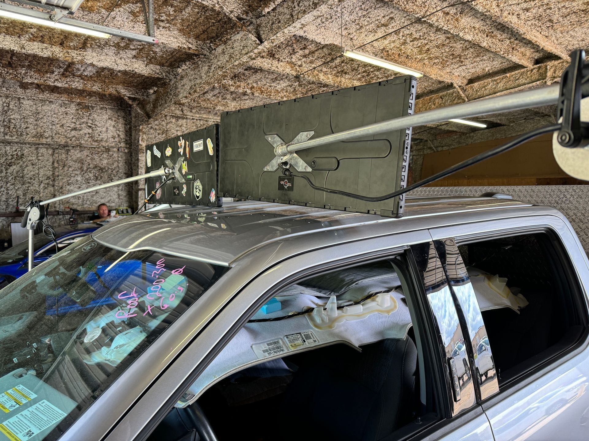 A silver truck is parked in a garage with a sign on the roof.