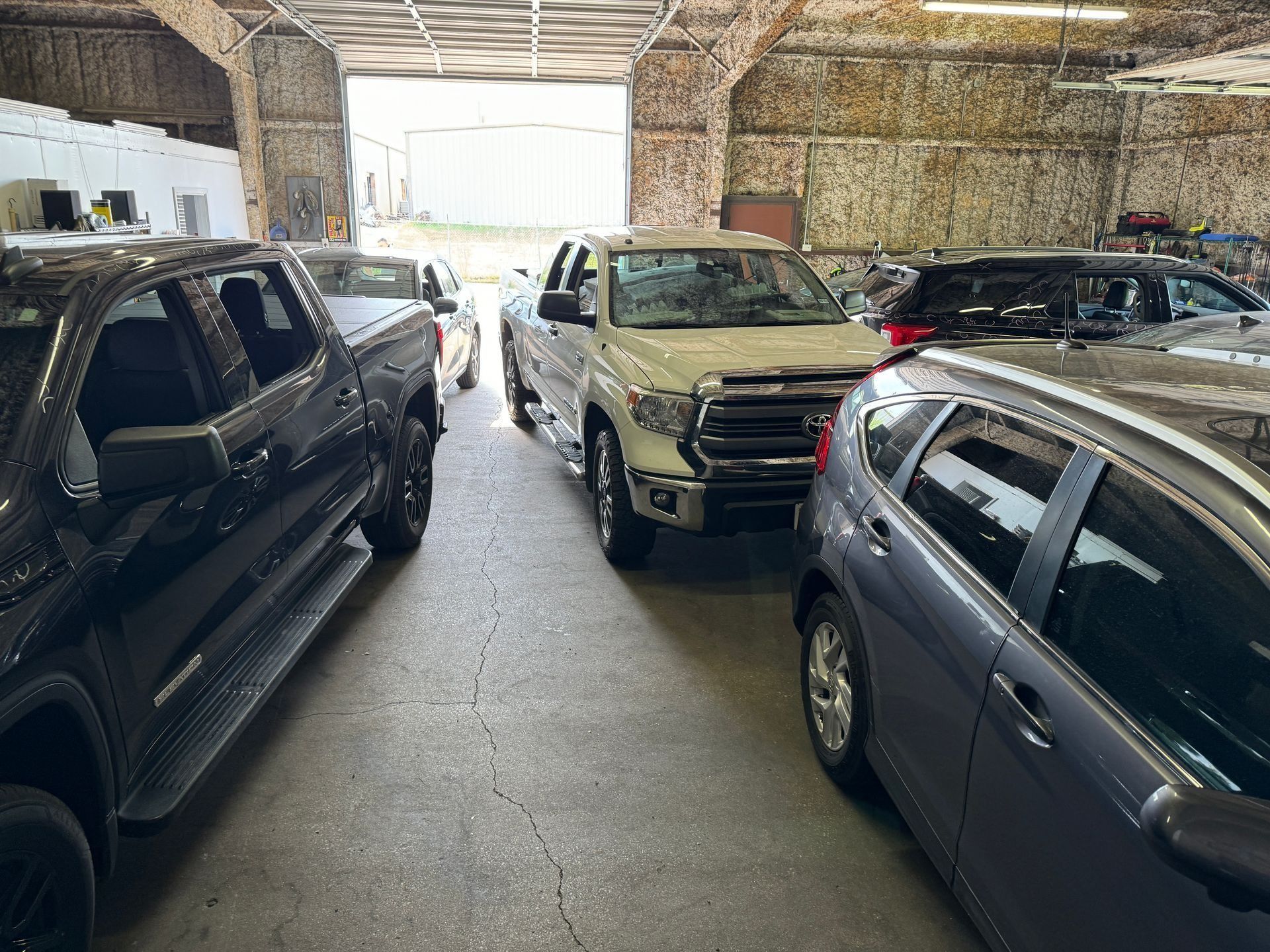 A row of cars are parked in a garage.