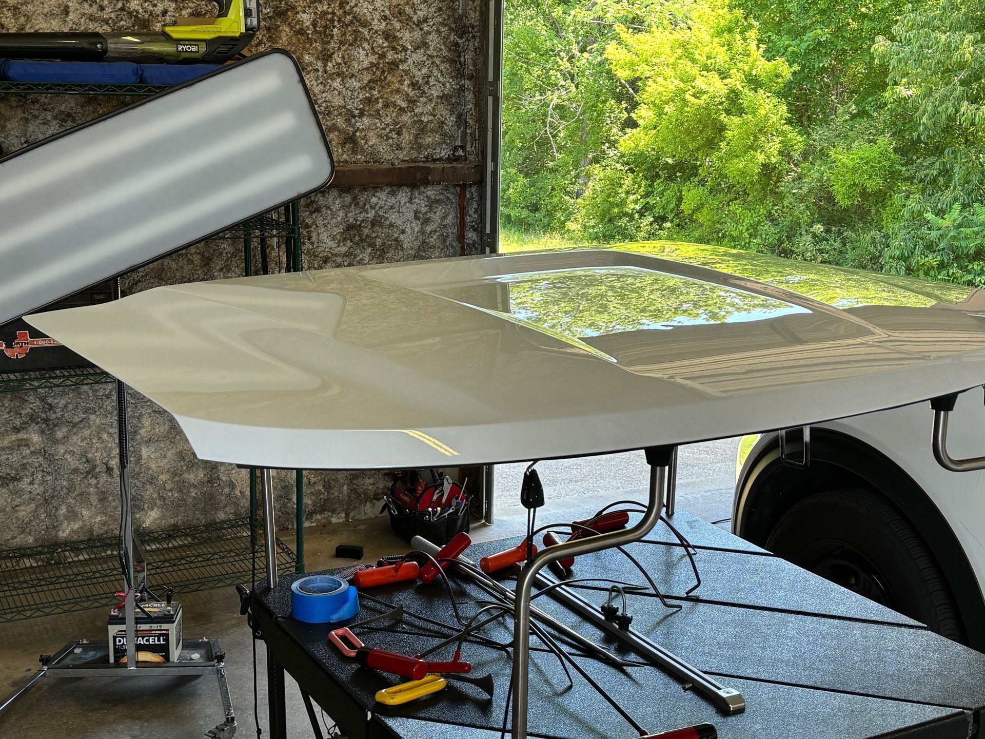 A car hood is sitting on top of a table in a garage.