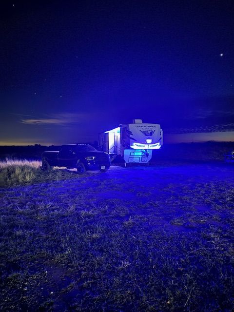 Man in blue shirt and white hat, smiling in front of an RV.