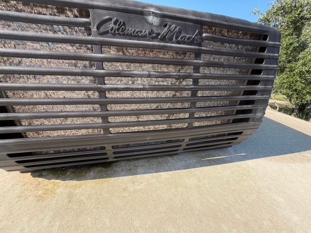 Close-up of a black metal gate with a decorative sign, outdoors on a sunlit driveway.
