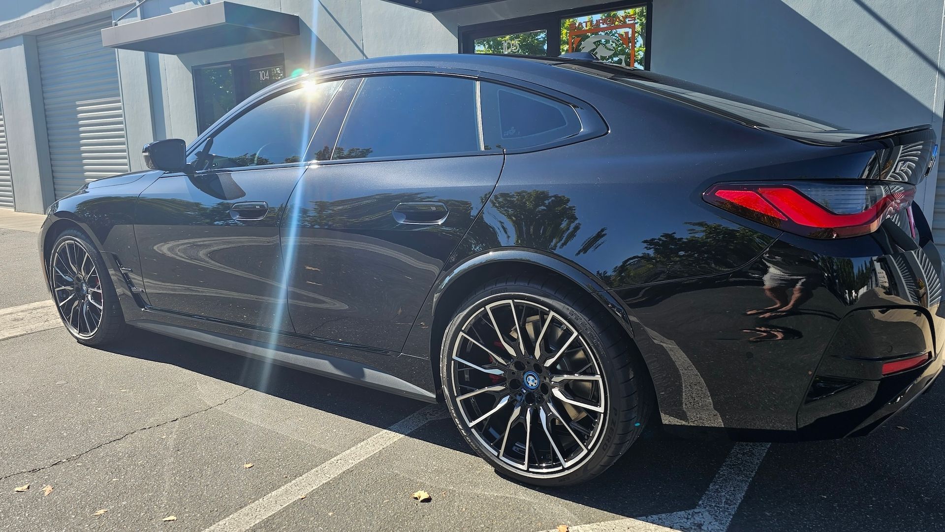 A black car is parked in a parking lot in front of a building.