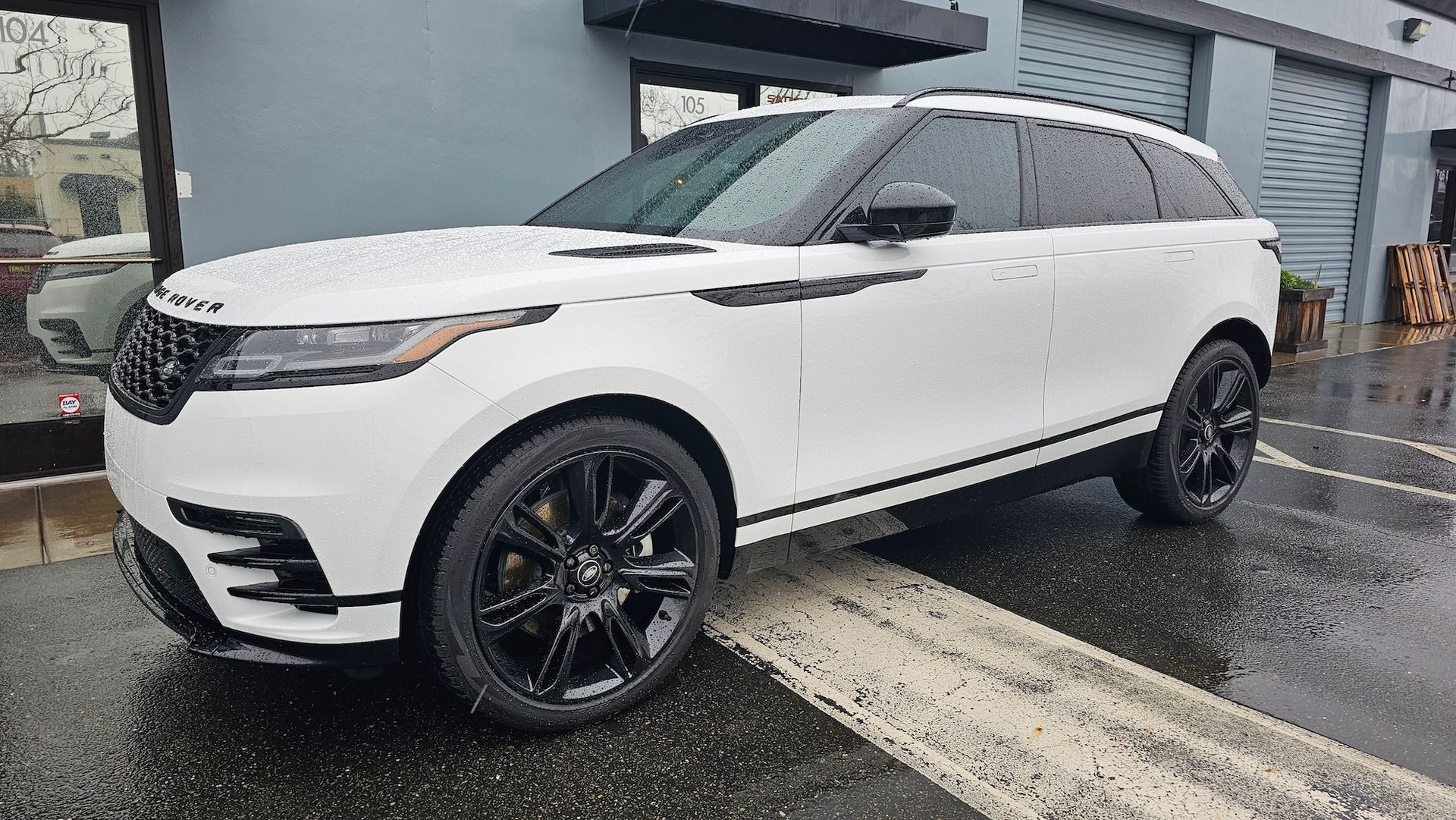A white range rover velar is parked in a parking lot in front of a building.
