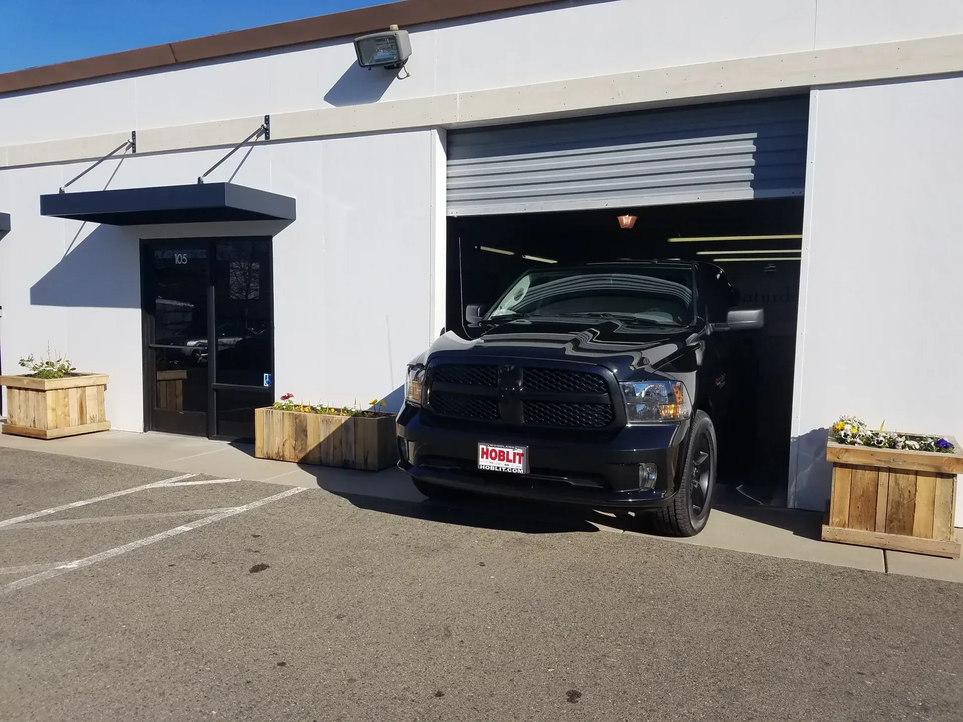 A black truck is parked in front of a white building.