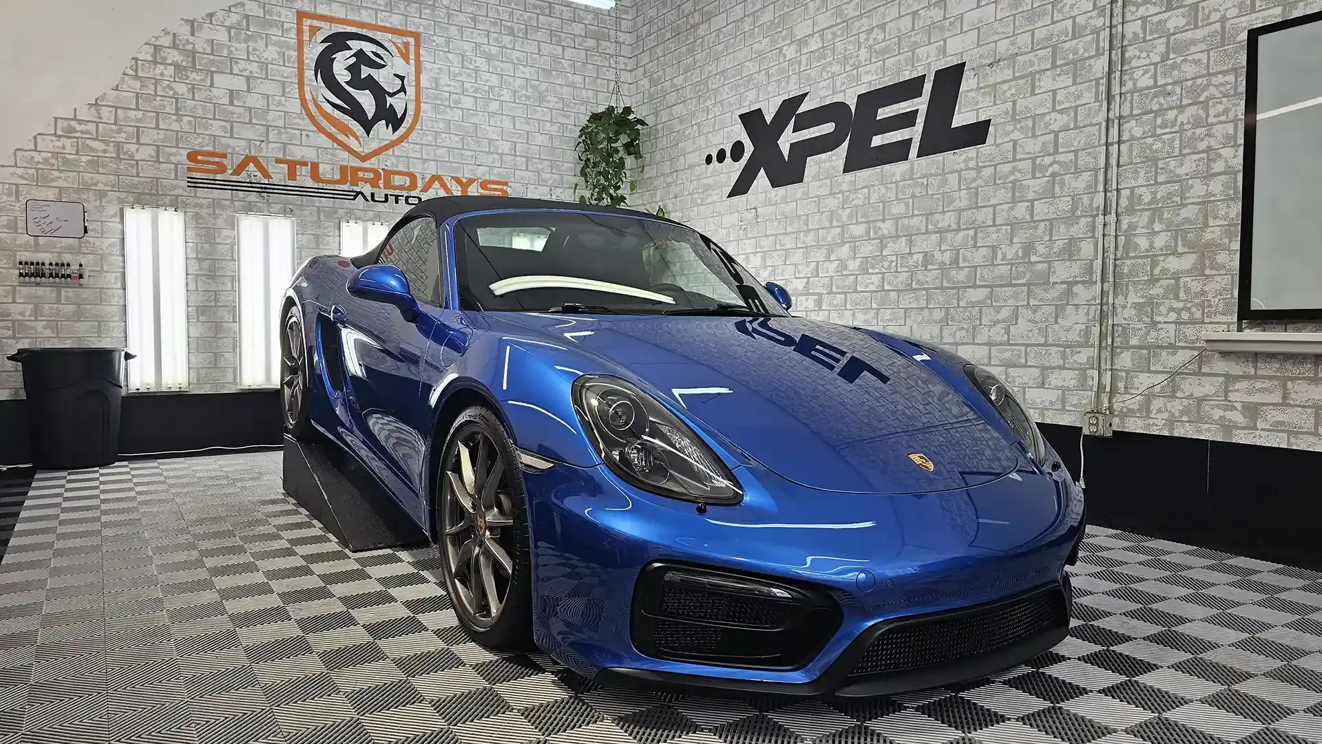 A blue porsche boxster is parked in a garage.