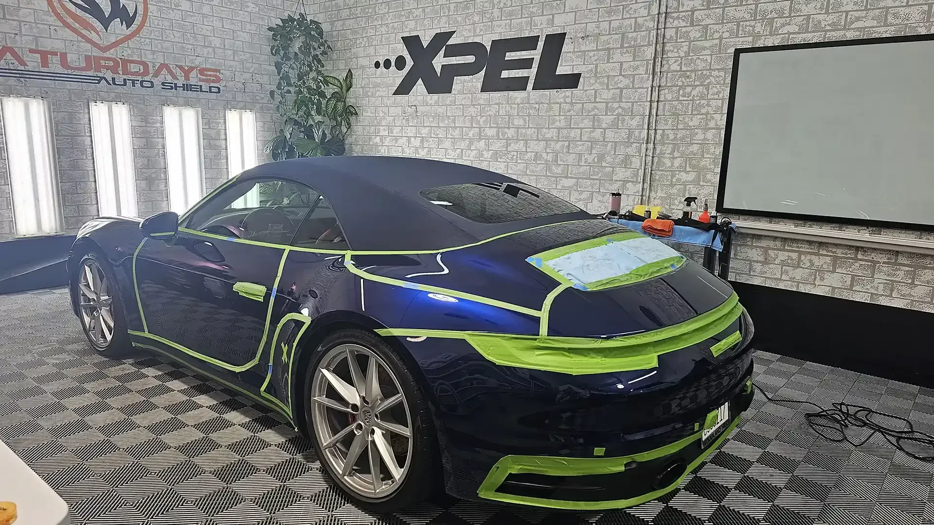 A blue and green sports car is sitting in a room.