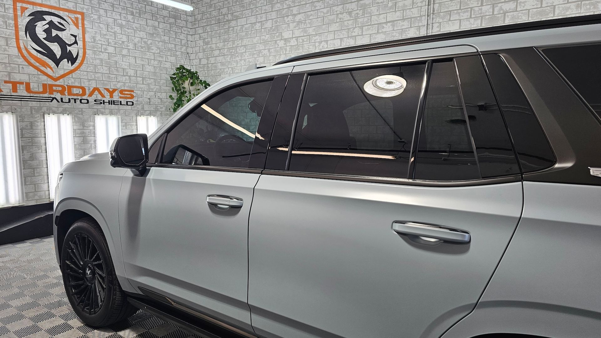 A silver suv with black windows is parked in a garage.