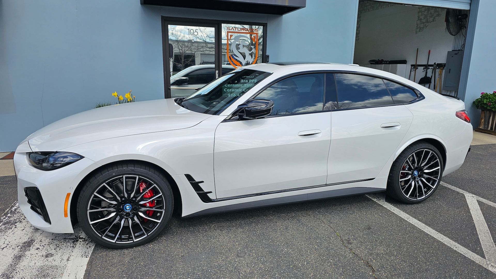 A white bmw 4 series is parked in a parking lot in front of a building.