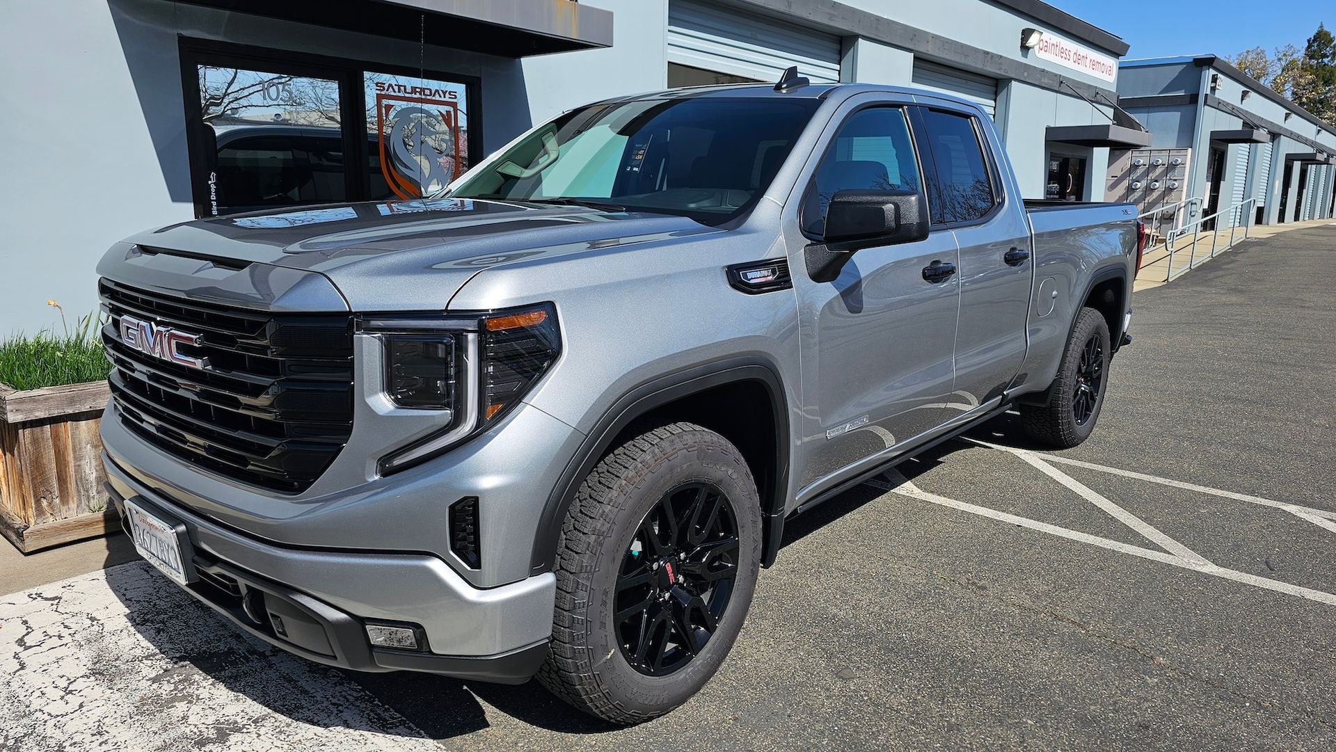 A gray gmc sierra pickup truck is parked in front of a building.