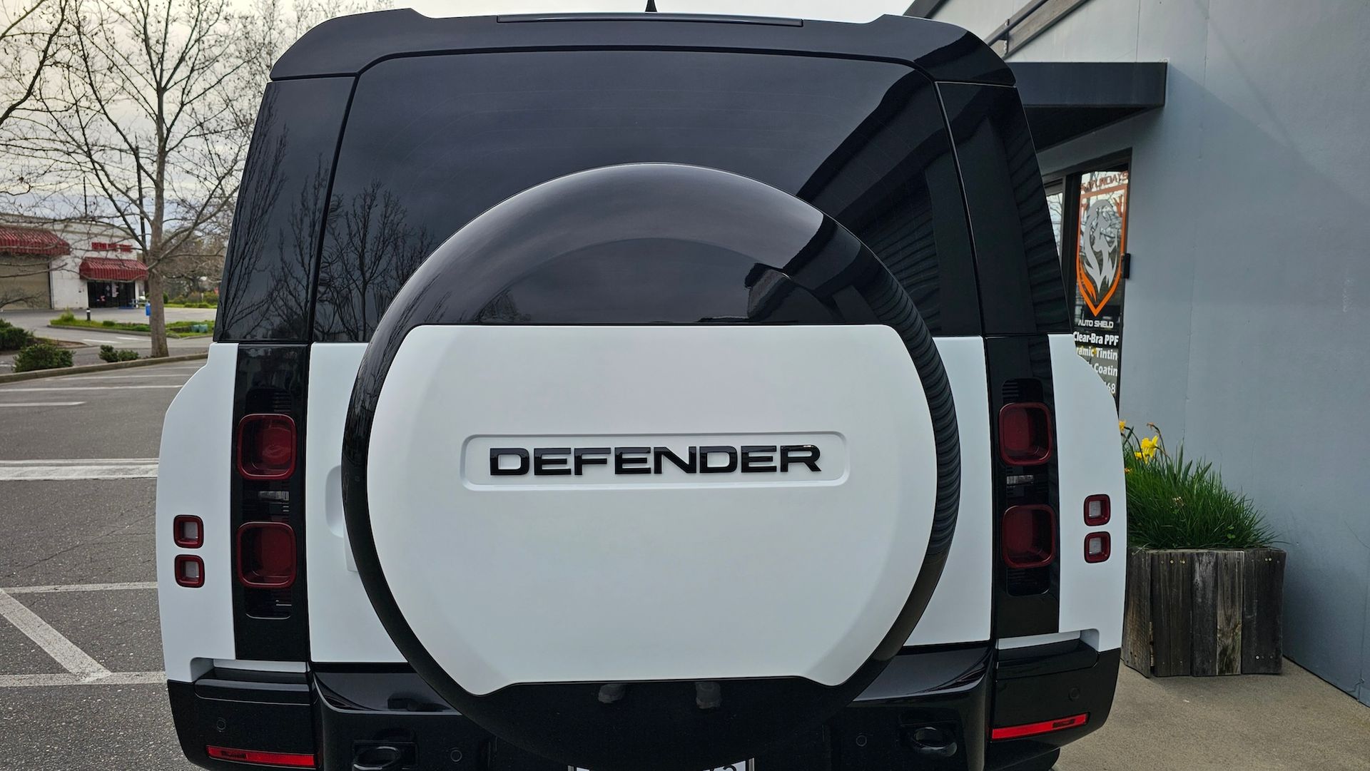 A white land rover defender is parked in a parking lot.