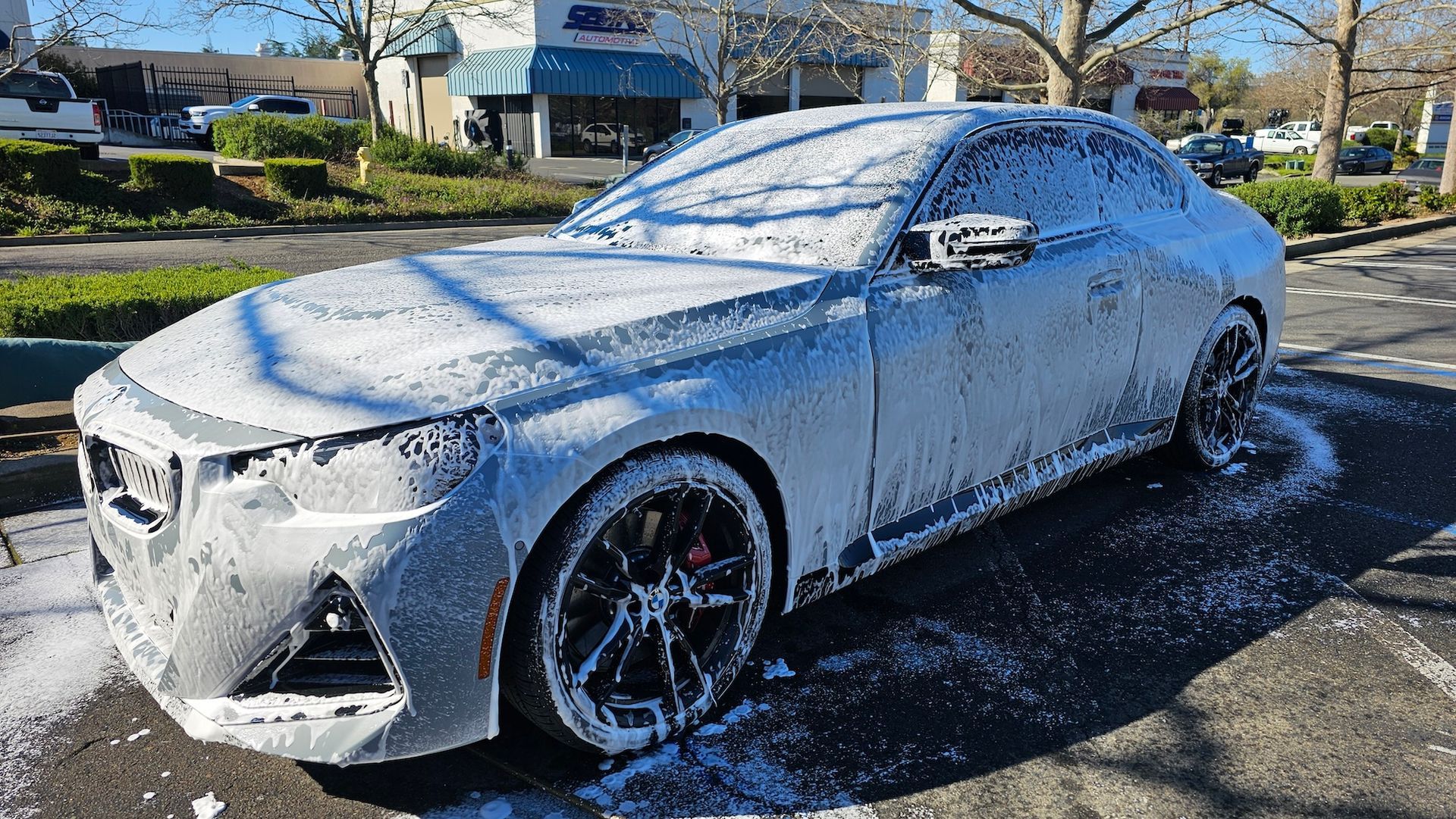 A car is covered in foam in a parking lot.