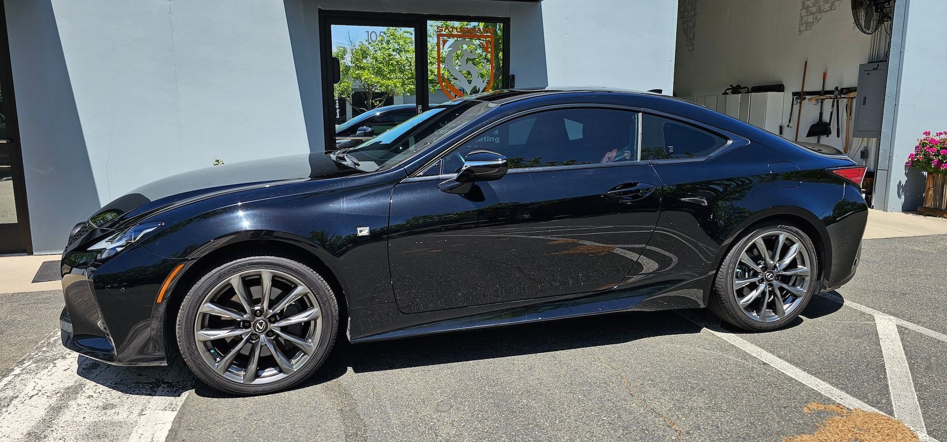 A black sports car is parked in a parking lot in front of a building.