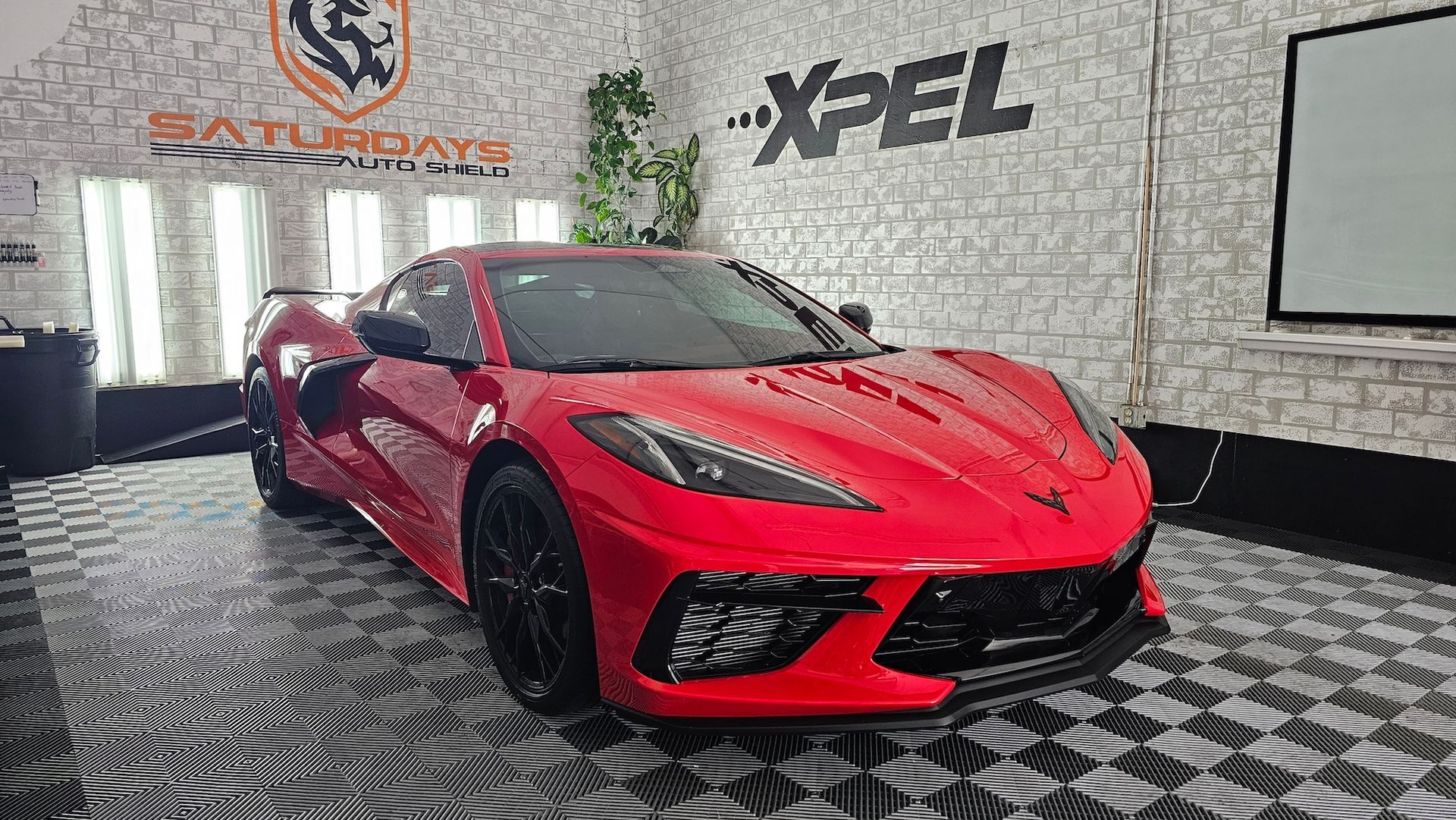 A red corvette is parked in a garage.