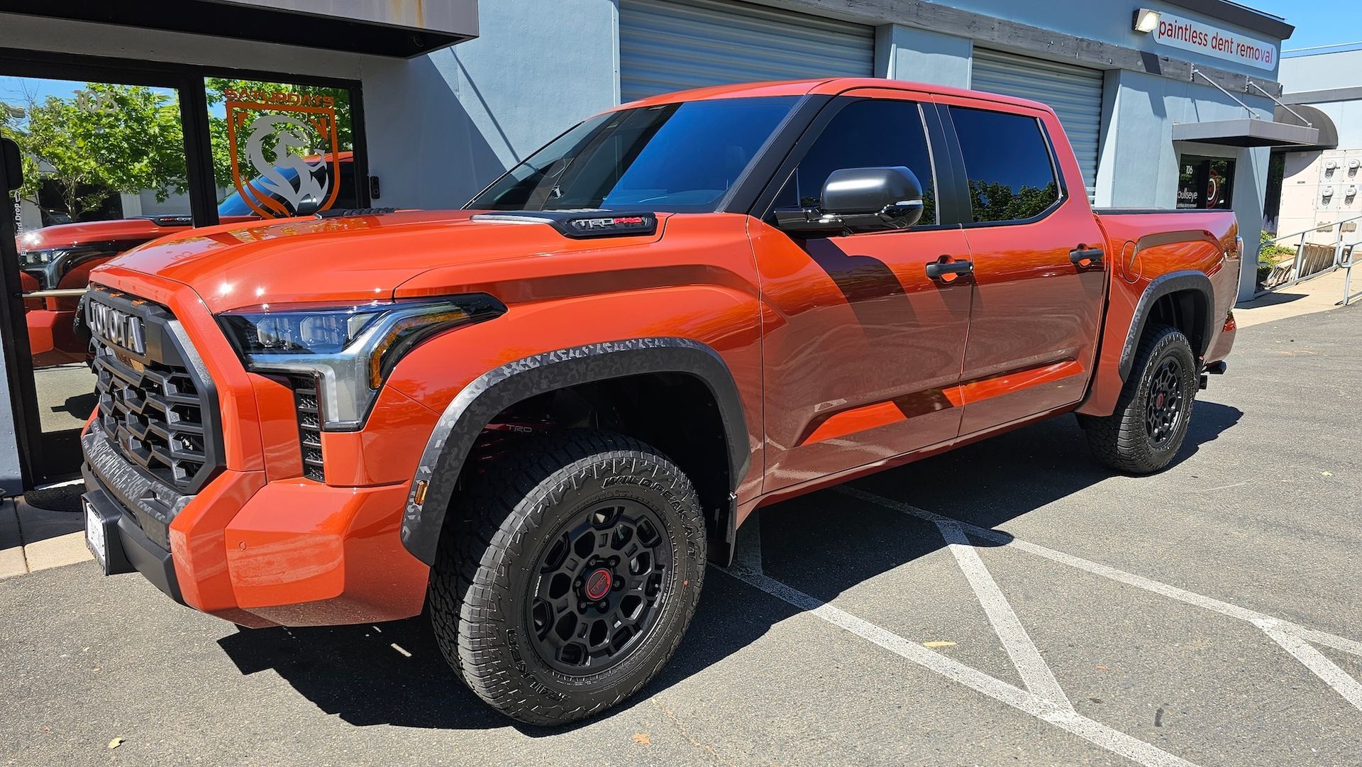 A red toyota tundra is parked in a parking lot in front of a building.