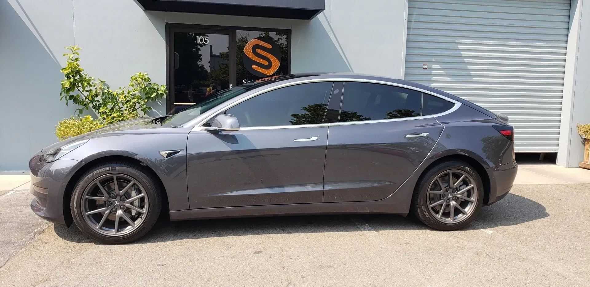 A tesla model 3 is parked in front of a building.