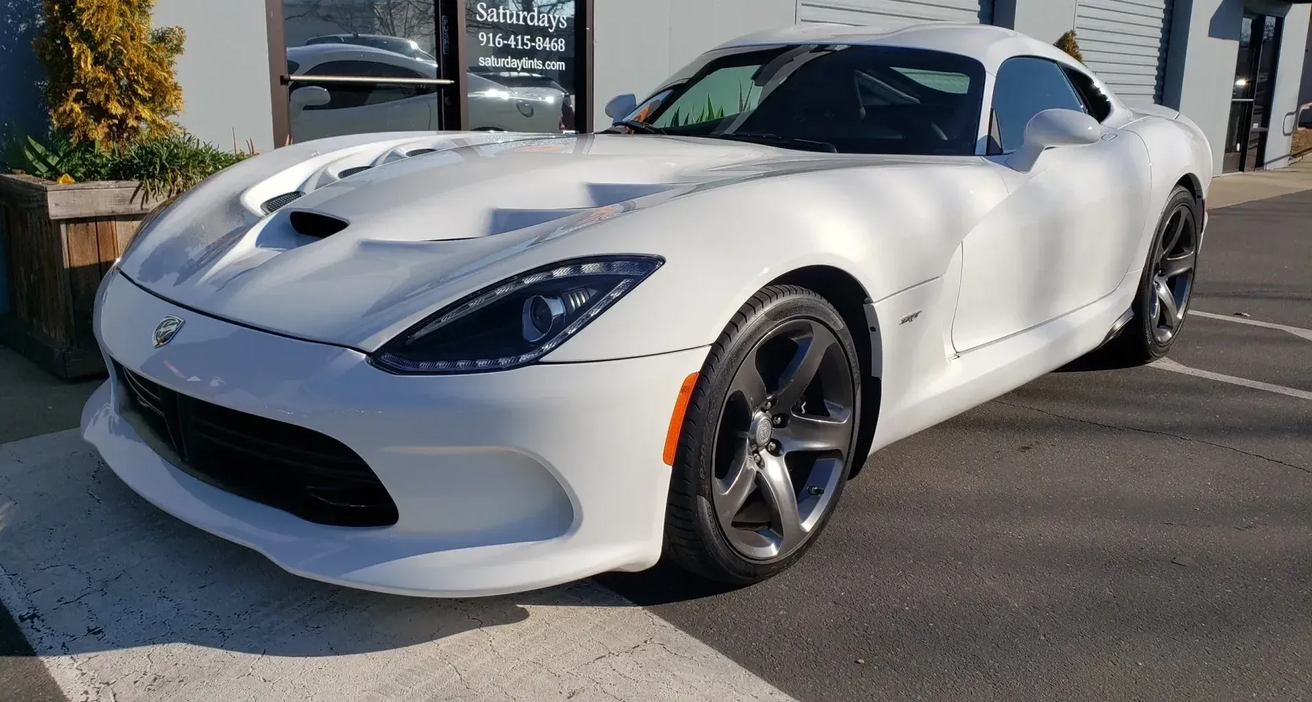 A white dodge viper is parked in a parking lot.