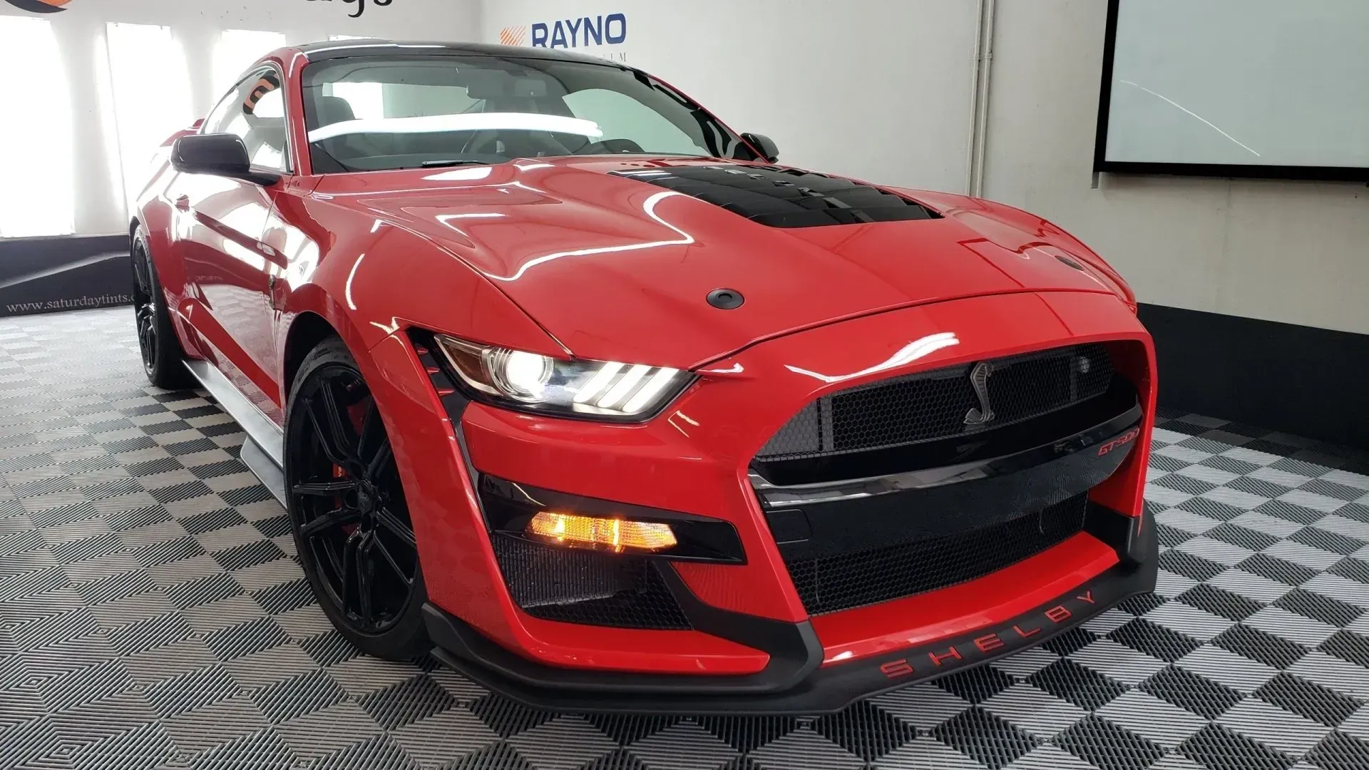 A red ford mustang is parked in a garage.