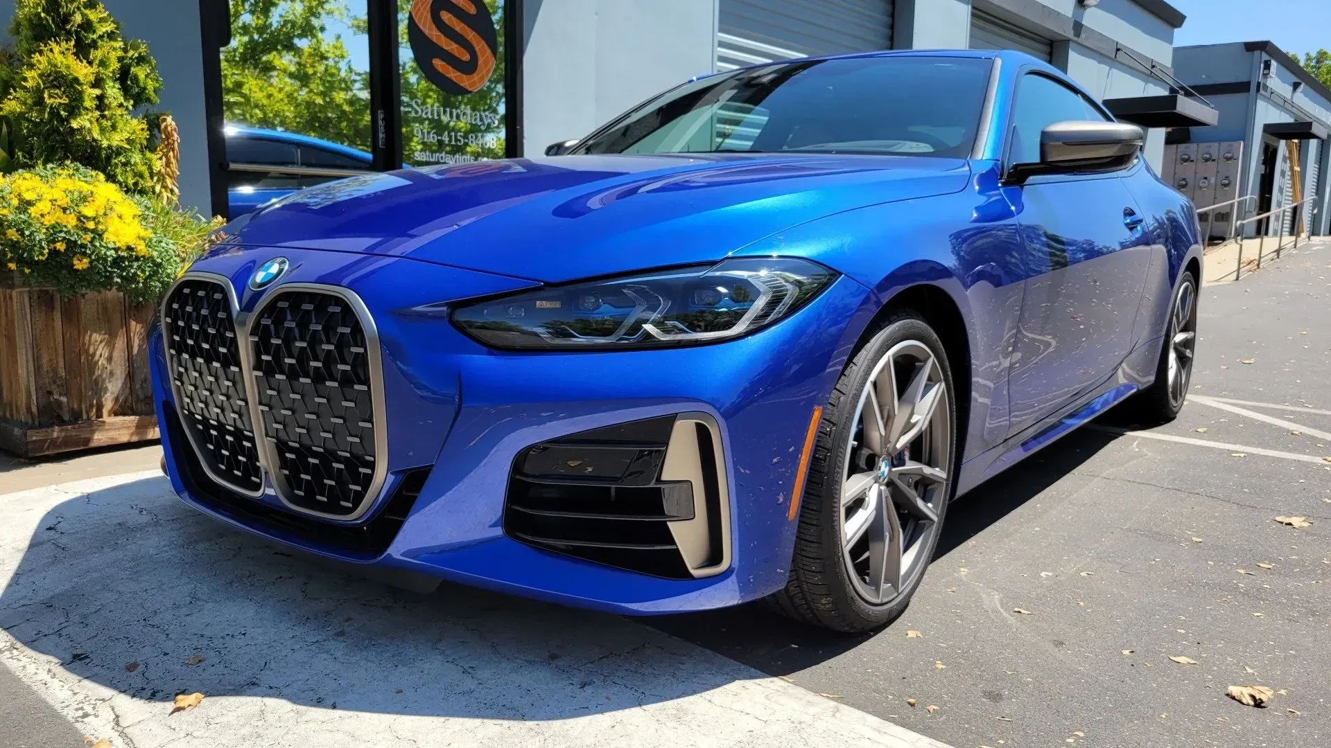 A blue bmw 4 series coupe is parked in a parking lot.