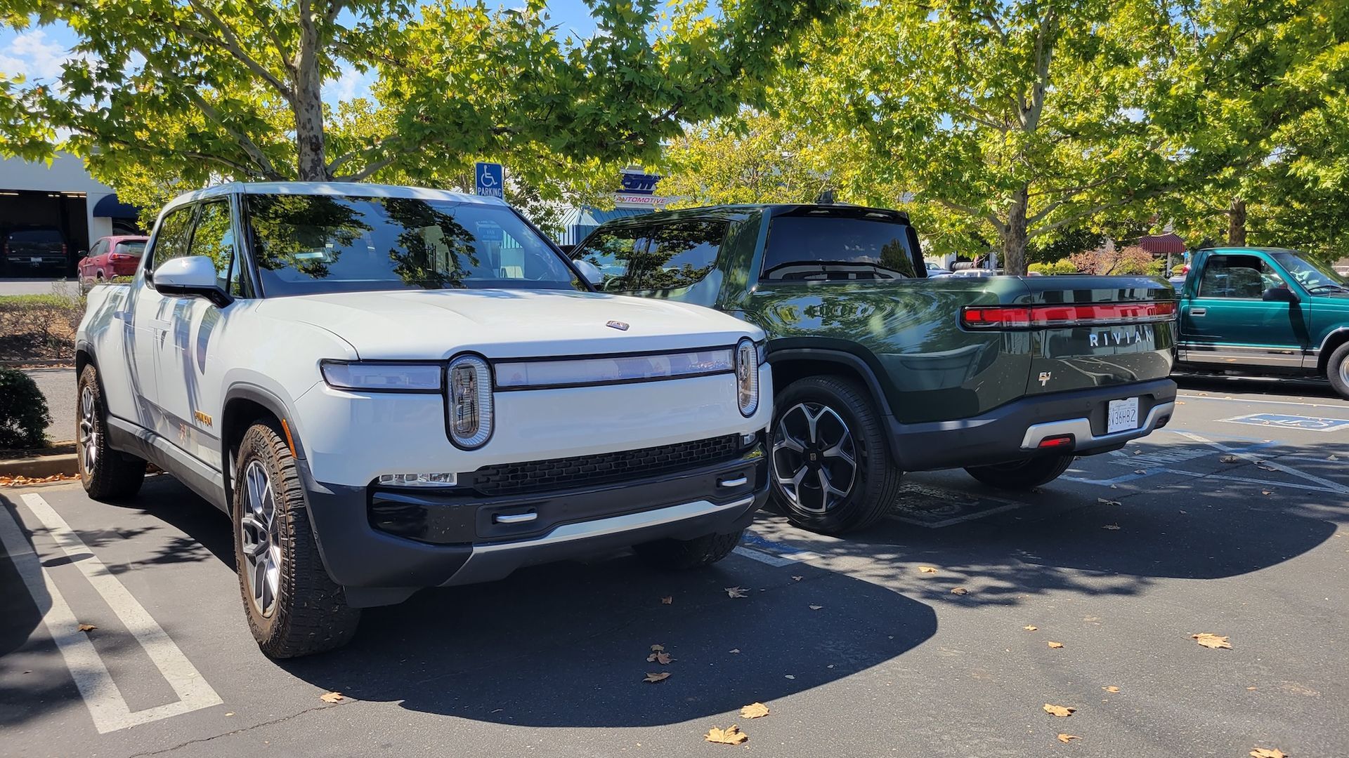 A white suv and a green truck are parked next to each other in a parking lot.
