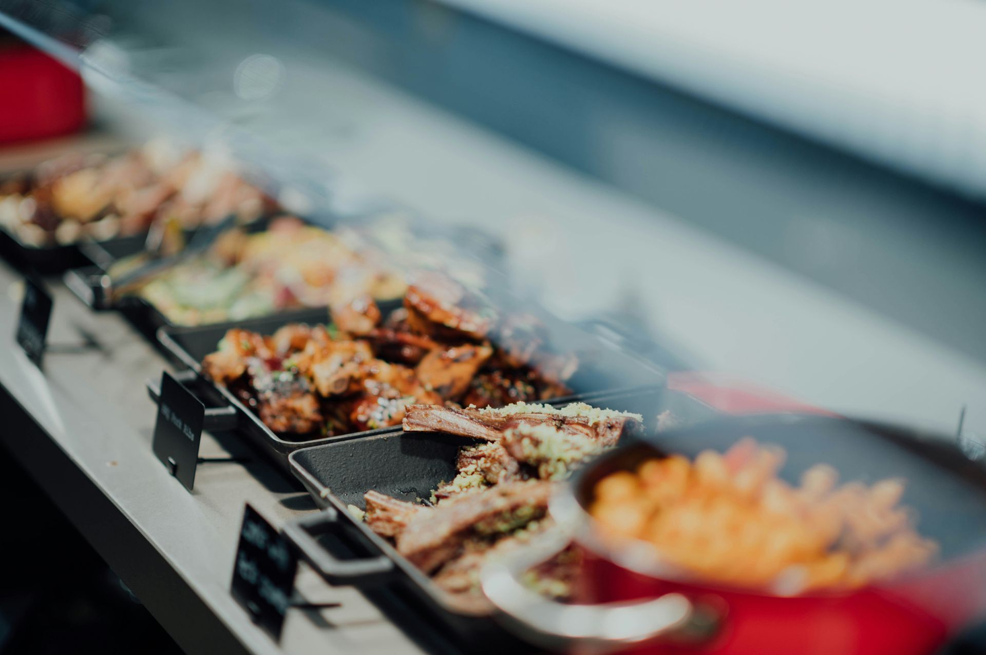 Buffet présenté avec divers plats dans des plateaux noirs derrière une vitre.