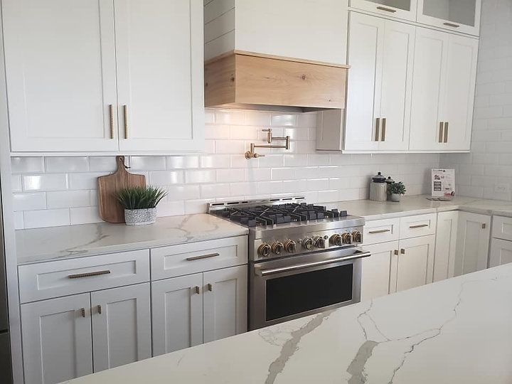 A kitchen with white cabinets and a stove top oven.