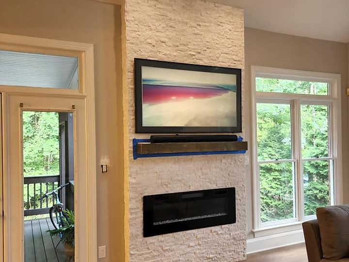 A living room with a fireplace and a flat screen tv on the wall.