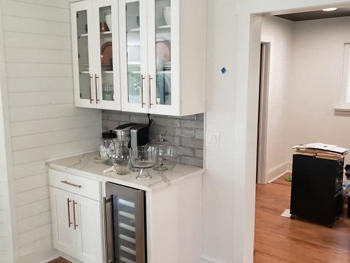 A kitchen with white cabinets and a wine cooler.