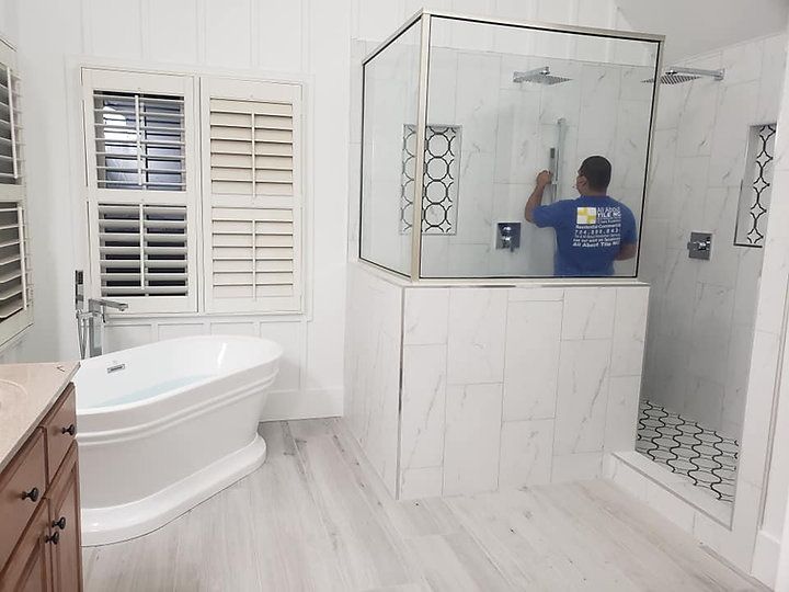 A man is standing in a bathroom next to a bathtub and shower.