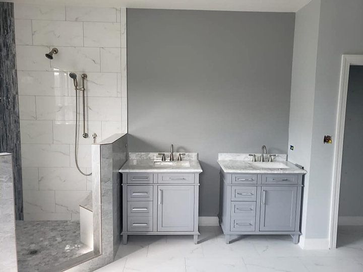 A bathroom with two sinks and a walk in shower.