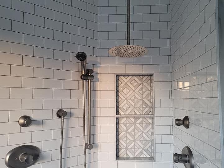 A bathroom with white tiles and a shower head