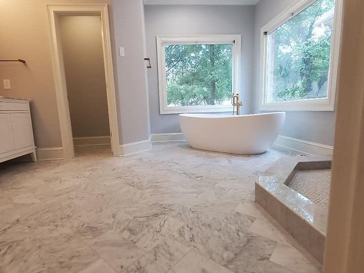 A bathroom with a tub , sink , and window.