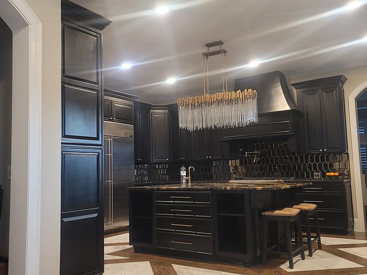 A kitchen with black cabinets , stainless steel appliances , and a large island.