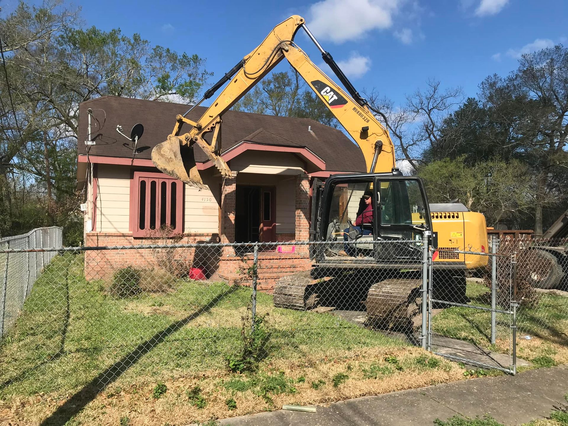 A large yellow excavator is demolishing a house.